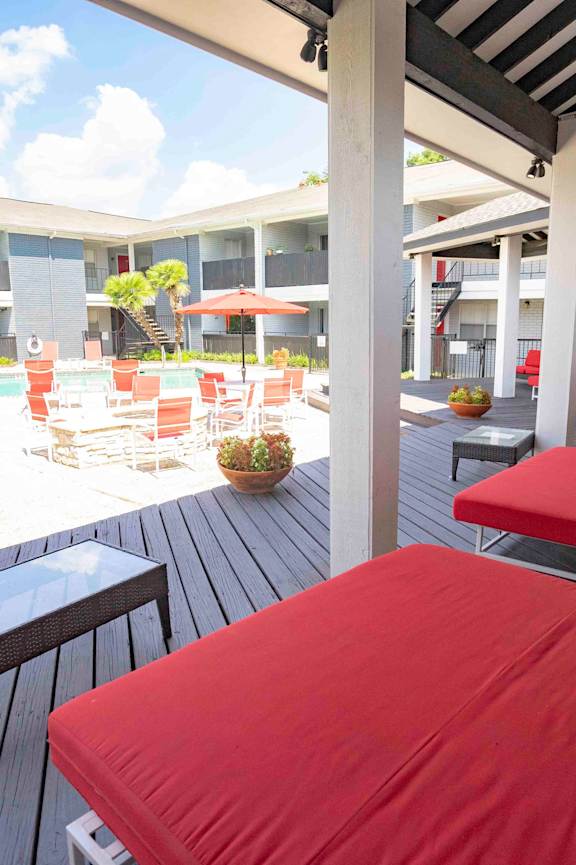 A patio with red cushioned chairs and tables.