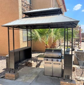 a patio with a grill and a gazebo