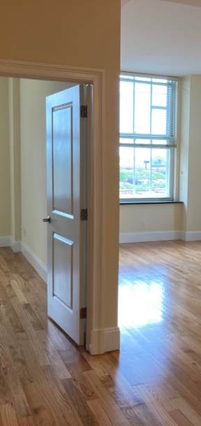 A room with wooden floors and a doorway leading to another room.