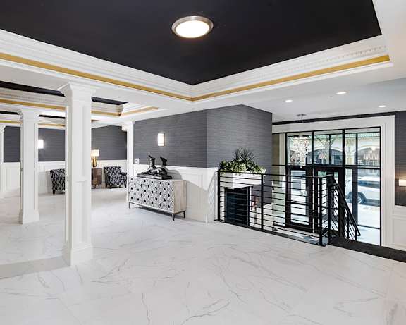 A spacious foyer with marble flooring and a black and white patterned sofa.