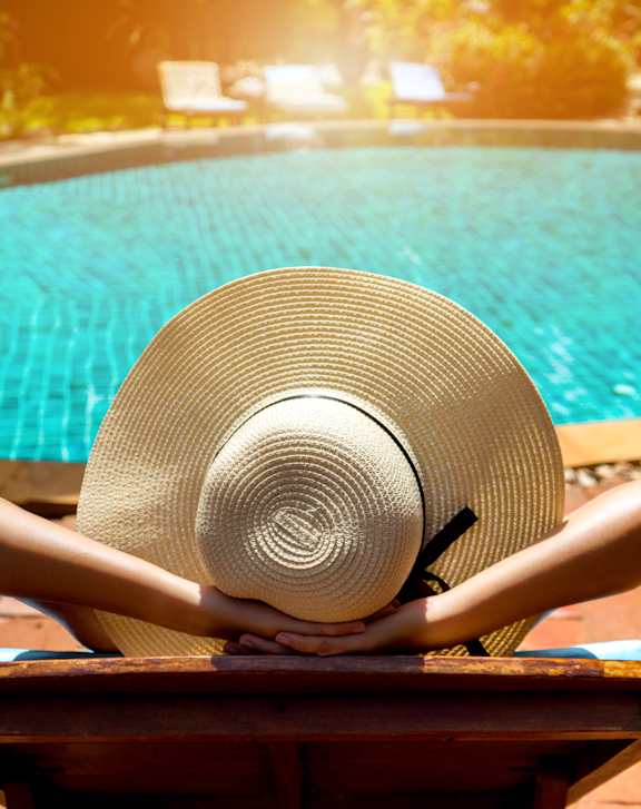 A straw hat is placed on a table by a pool at Whisper Lake Apartments, Winter Park, 32792