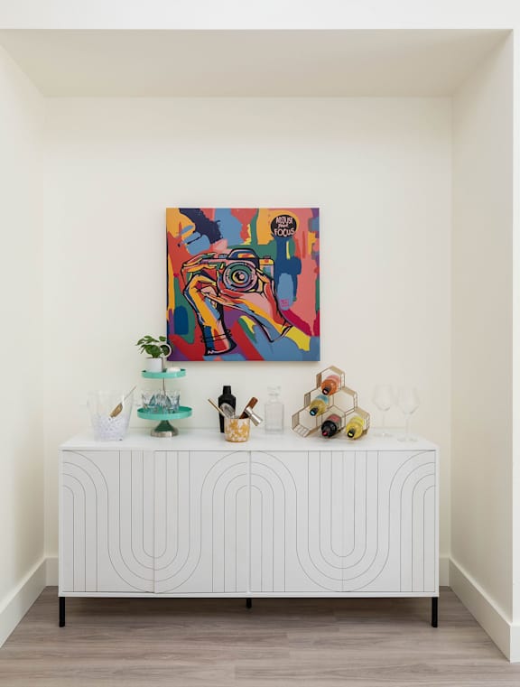 A white bed with a painting above it.