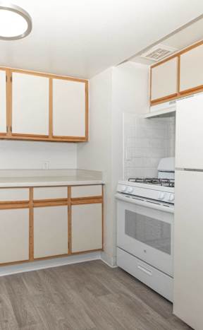 A kitchen with white appliances and wooden cabinets.