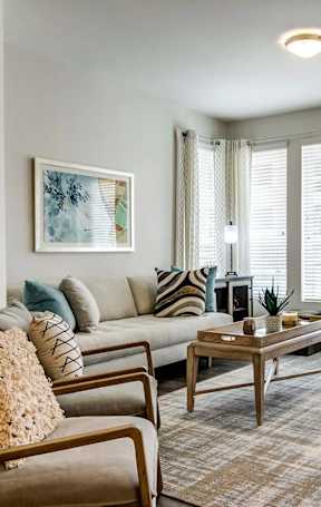 A living room with a brown couch, a coffee table, and a painting on the wall.
