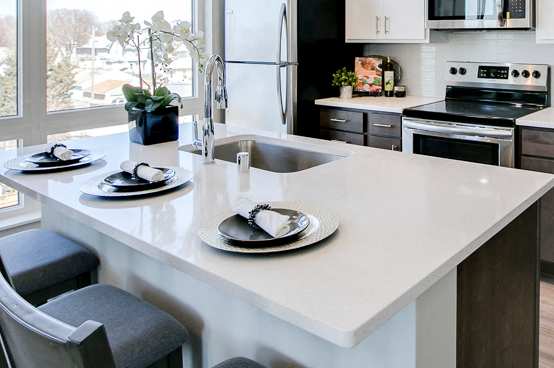 View of kitchen with white and dark contemporary cabinets and quartz countertops at The Central apartments near downtown Minneapolis MN 55408
