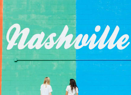 two women walking in front of a blue wall written on it