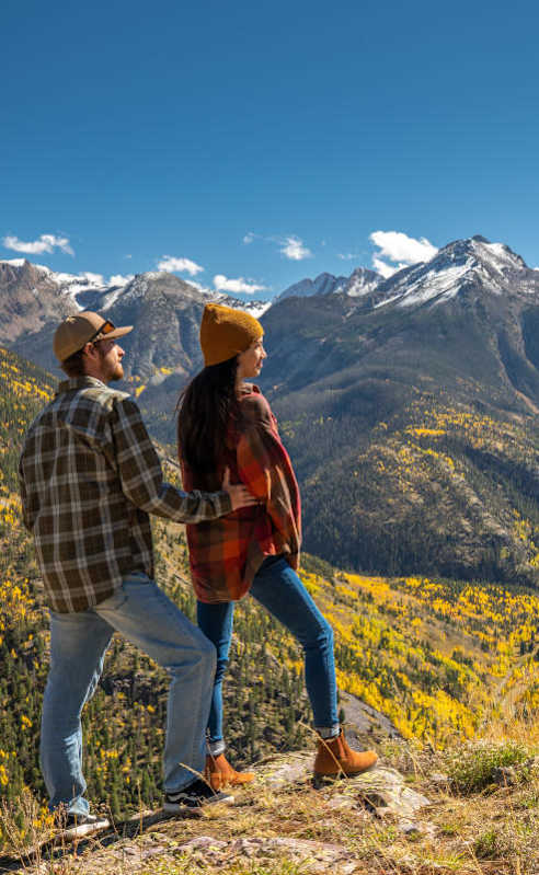 Two people standing on a mountain top looking at the view.