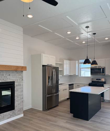 A modern kitchen with a black island and a fireplace.