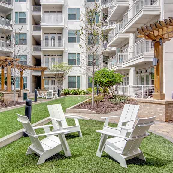 a courtyard with chairs and tables in front of an apartment building