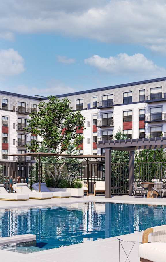A pool surrounded by lounge chairs and umbrellas in front of a multi-story apartment building.