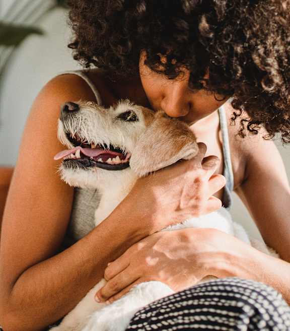 Woman with curly hair is hugging a small dog at The Bosk Apartment Homes, Woodbury, MN