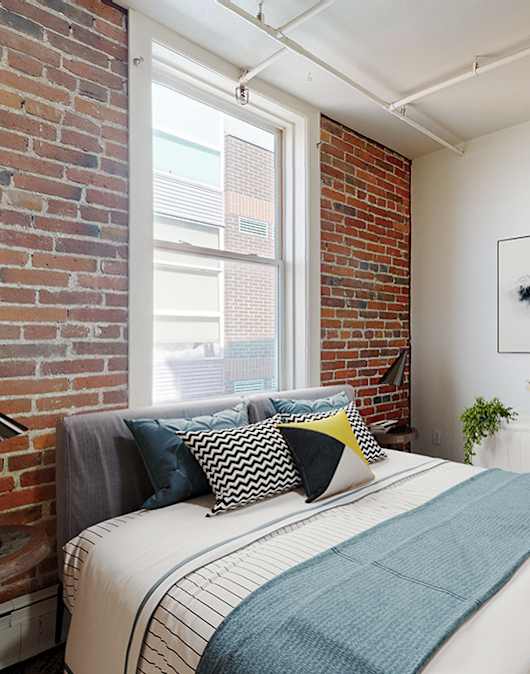 A bedroom with a bed, pillows, a lamp, and a painting on the wall.