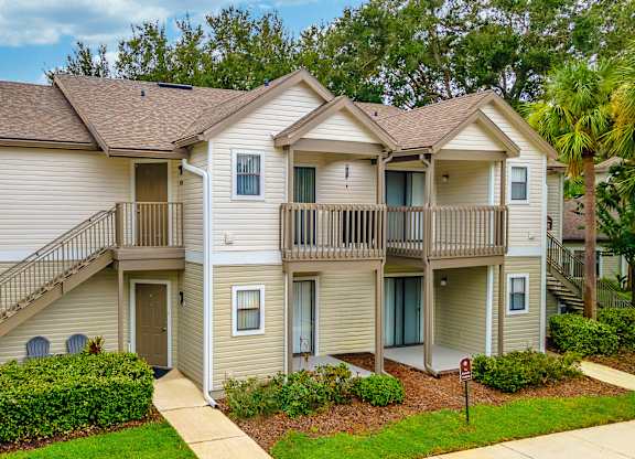 A two-story apartment building with a brown roof and beige walls.