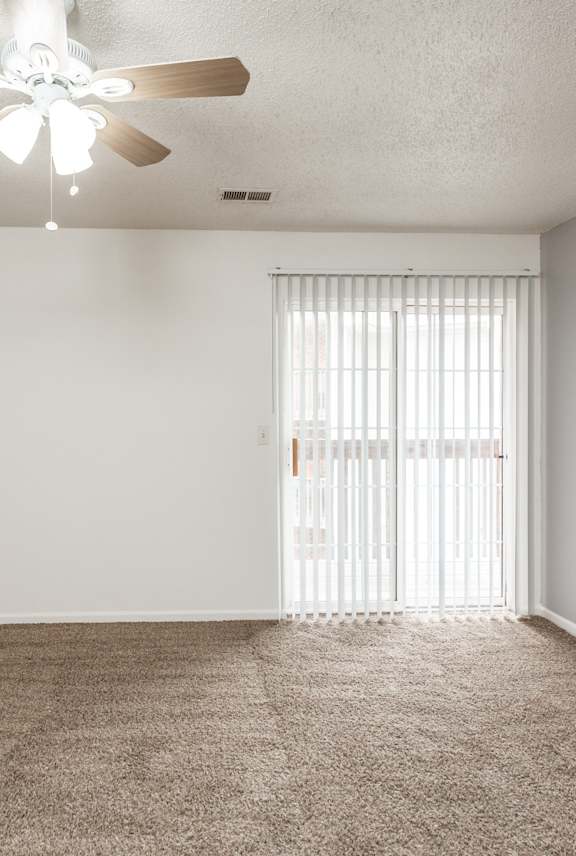 A room with a ceiling fan and carpeted floor.