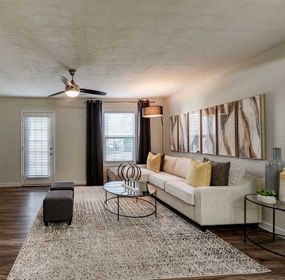 A living room with a yellow couch and a rug.
