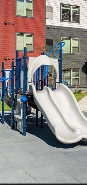 A playground with a white slide and a blue climbing frame.