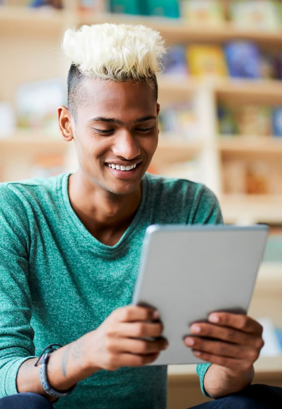 this is a photo of a young man browsing a tablet at the local bookstore.