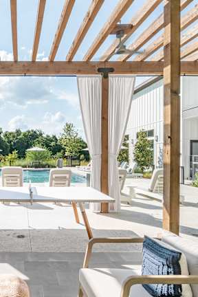 A wooden pergola over a patio with a table and chairs.