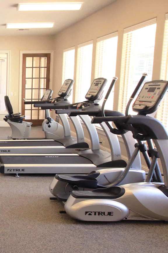 A gym with a variety of equipment including treadmills, weights, and exercise machines.