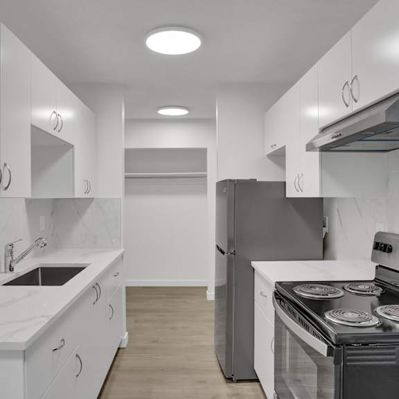 A modern kitchen with white cabinets and stainless steel appliances.