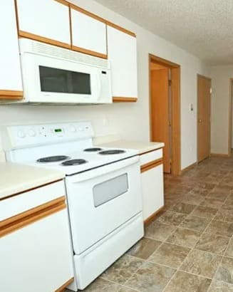 A kitchen with white appliances and brown cabinets.