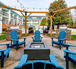 a patio with blue chairs and a fire pit