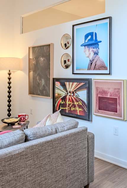 A living room with a red sofa, a chair, and a picture frame on the wall.