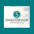 a logo for shadowwood apartments with a green sky background