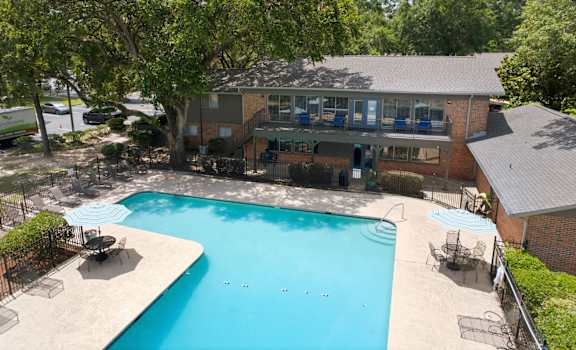 A swimming pool surrounded by trees and a building.