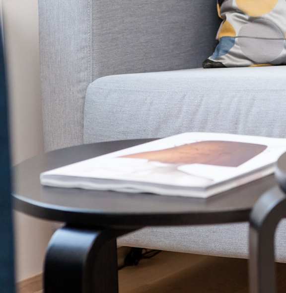 A white couch with a wooden table in front of it and a pair of shoes on the floor.