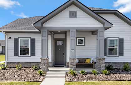 A house with a grey front and a brown bench.