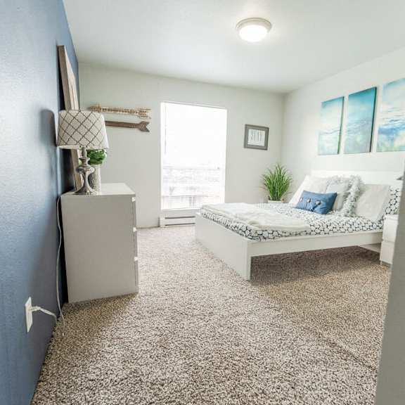 A bedroom with a bed, dresser, and window.