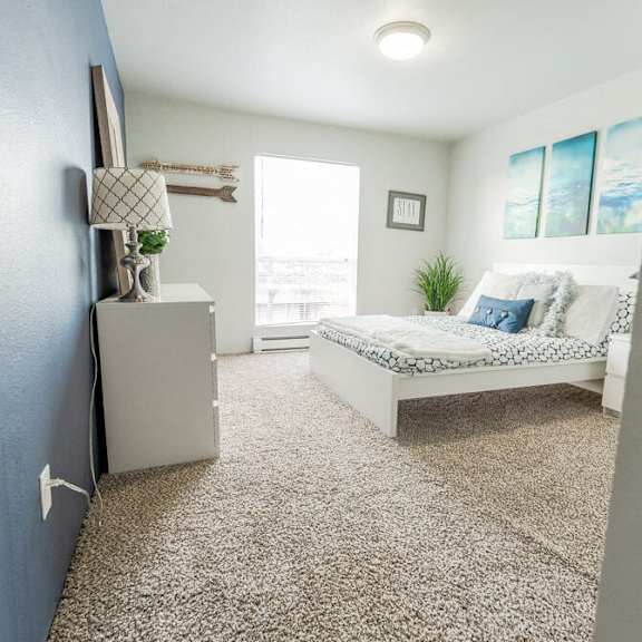 A bedroom with a bed, dresser, and window.