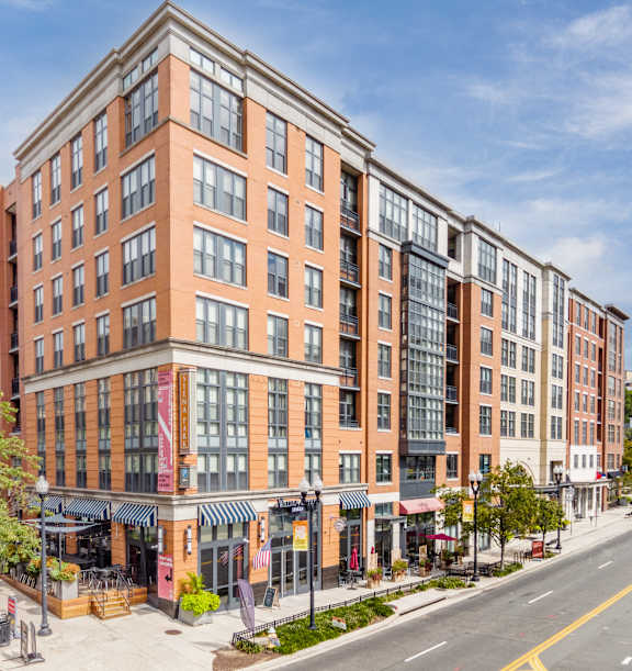 A street view of a multi-story building with a parking lot in front.