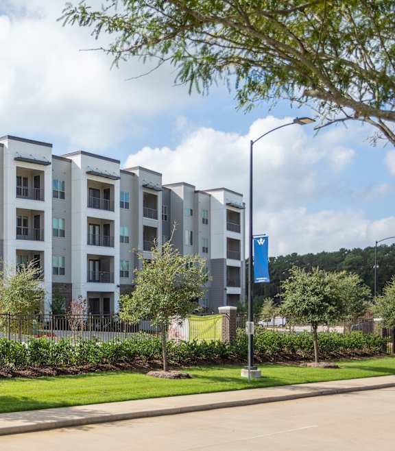 A row of modern apartment buildings with a blue sign on a lamp post.
