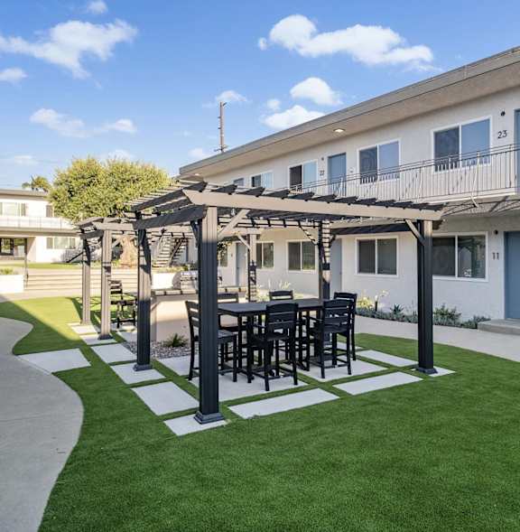 A patio with a table and chairs under a pergola.