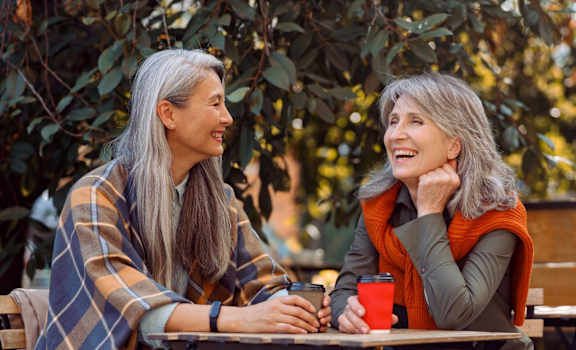 two women sitting at a table in a park