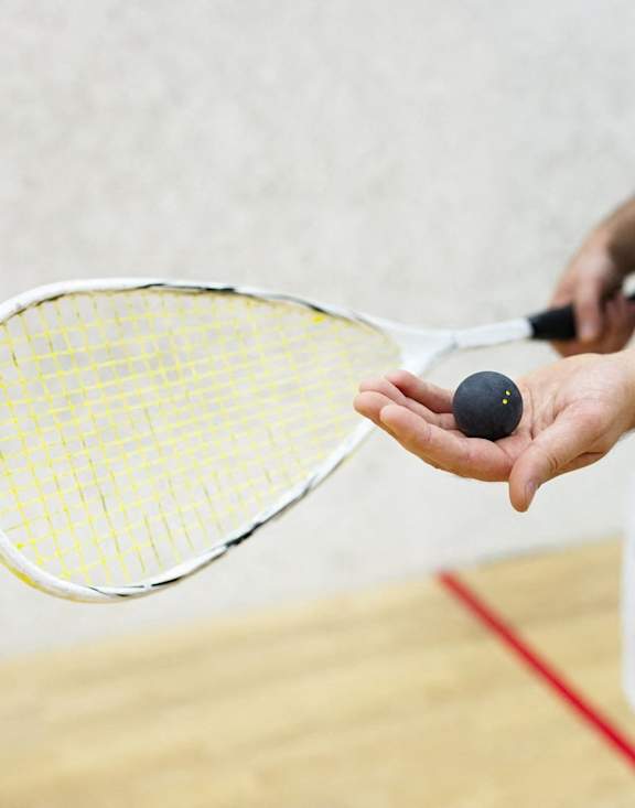 Person Holding Racquet and Ball