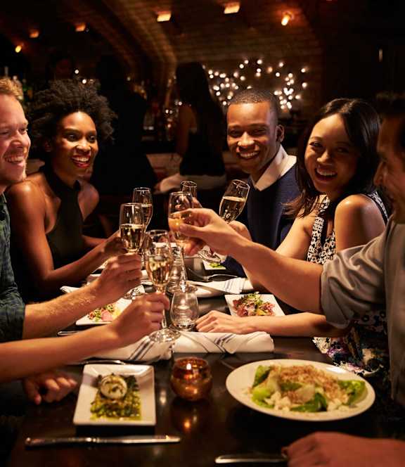 Group of Friends Toasting with Champagne Glasses at a Dinner Table