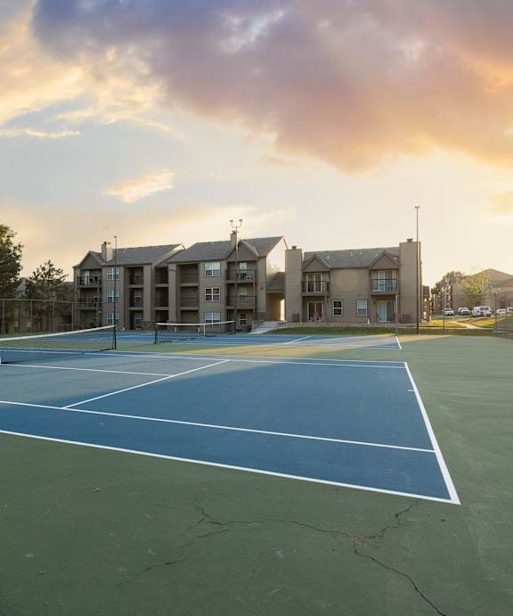 Tennis courts at The Lakes community, with apartment buildings in the background and a well-maintained playing surface.