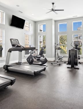 the gym with treadmills and other exercise equipment in a building with windows