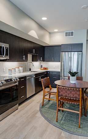 A modern kitchen with dark wood cabinets and stainless steel appliances.