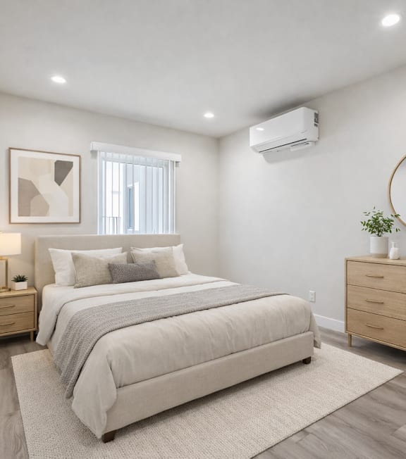 A well-lit bedroom with a large bed and a painting on the wall.