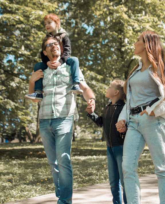 A family of four is walking in a park at Meadowlark Place Apartments, Grimes, IA,  50111