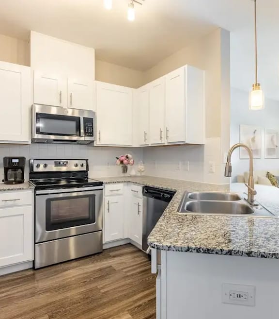 A kitchen with white cabinets and a granite countertop.