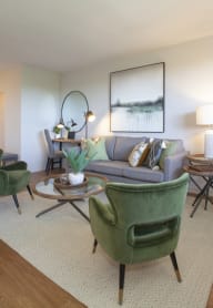 a living room with a gray couch and green chairs