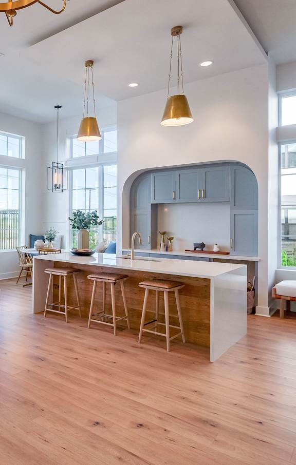 A modern open plan living and kitchen area with wooden floors and furniture.
