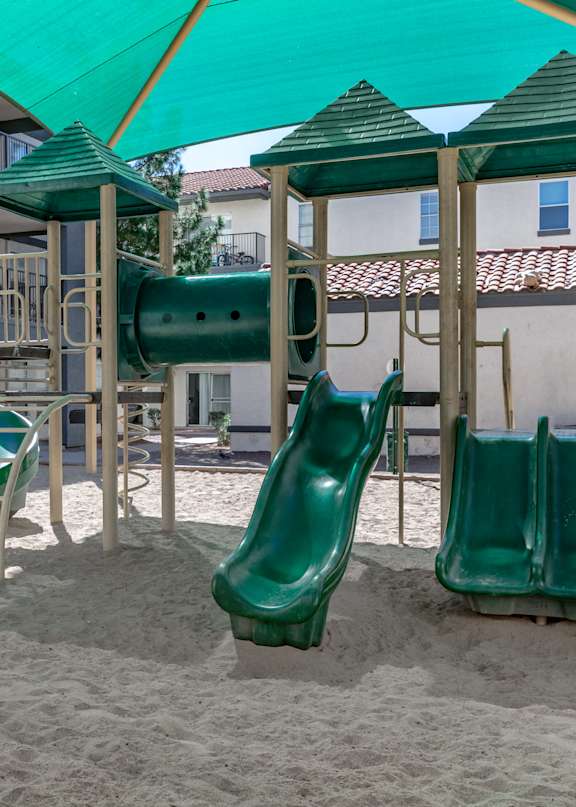 A playground with a green slide and a green canopy.