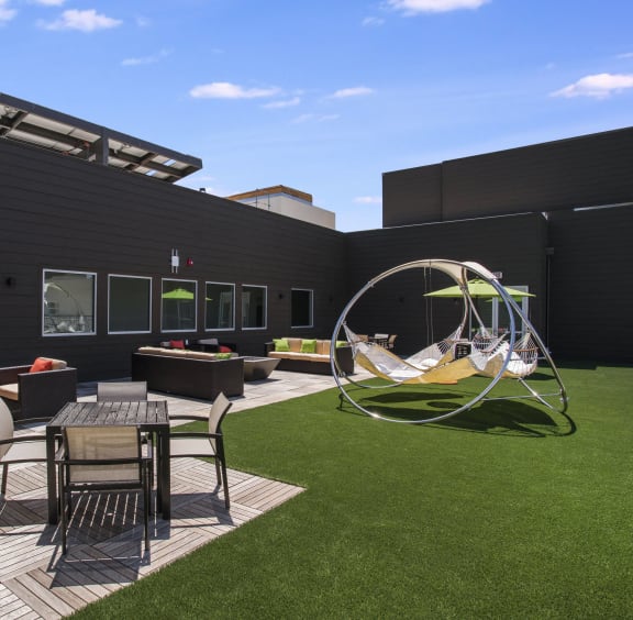 a lounge area on the roof of a building with a hammock and a swing