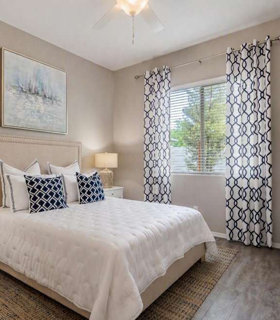 A bedroom with a bed, nightstand, and a plant.